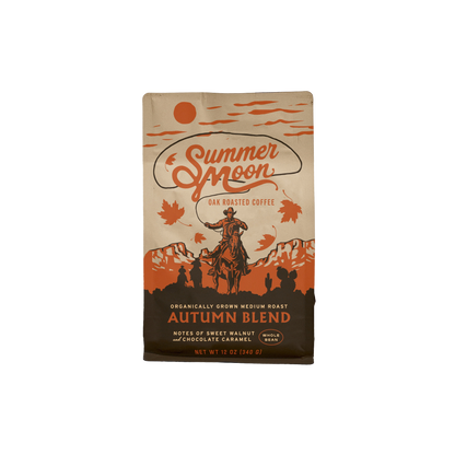 A bag of Summer Moon Autumn Blend Oak Roasted Coffee on a plain white background. The packaging features a vintage western design with an illustration of a cowboy on a horse, mountains, and orange autumn leaves on a tan background.
