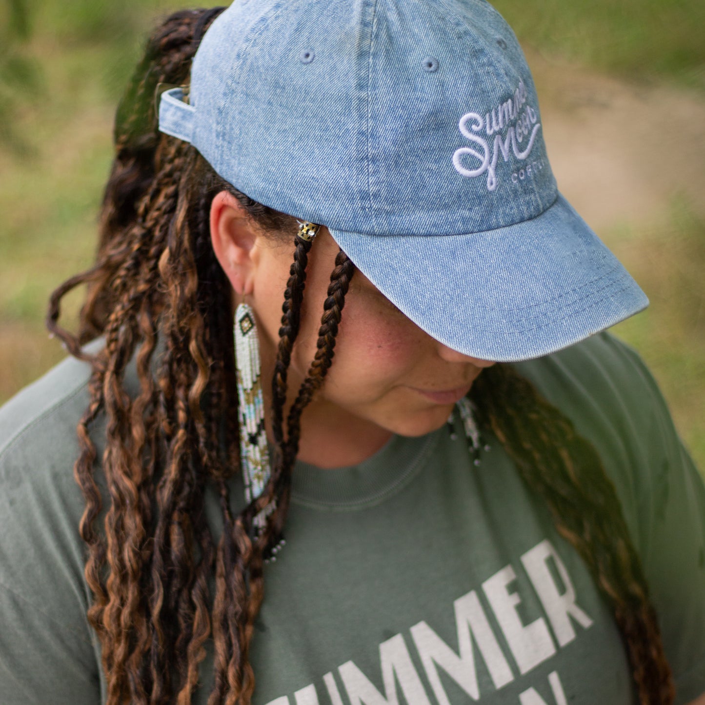 A profile view of a woman wearing a light wash denim dad hat.