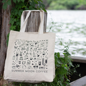 A canvas tote bag with a simple black doodle design, featuring coffee related gadgets and references to Summer Moon Coffee.